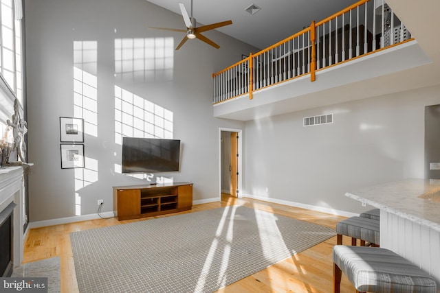 living room featuring ceiling fan, light hardwood / wood-style flooring, and a high ceiling