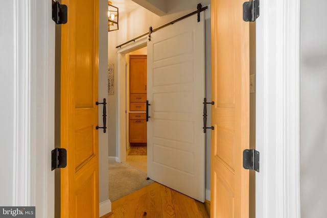 corridor with a barn door and light hardwood / wood-style flooring