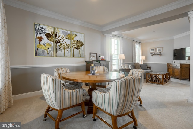 carpeted dining area featuring crown molding and decorative columns