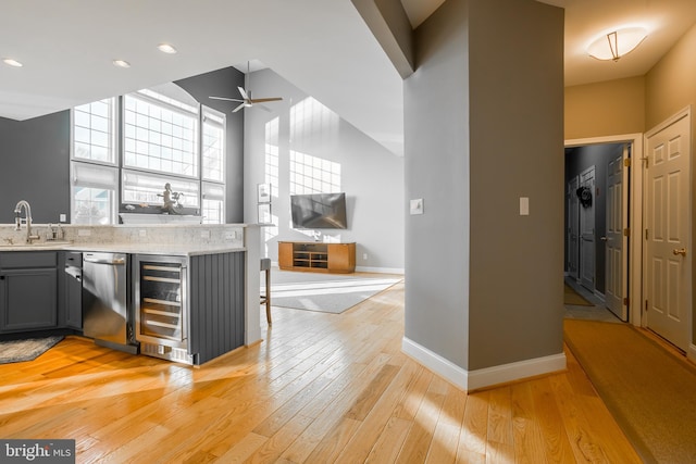 kitchen featuring sink, light wood-type flooring, gray cabinets, dishwasher, and beverage cooler