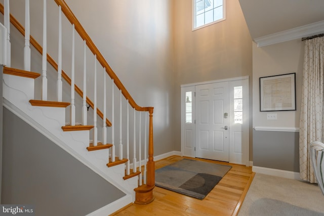 entrance foyer featuring crown molding, a towering ceiling, and hardwood / wood-style floors