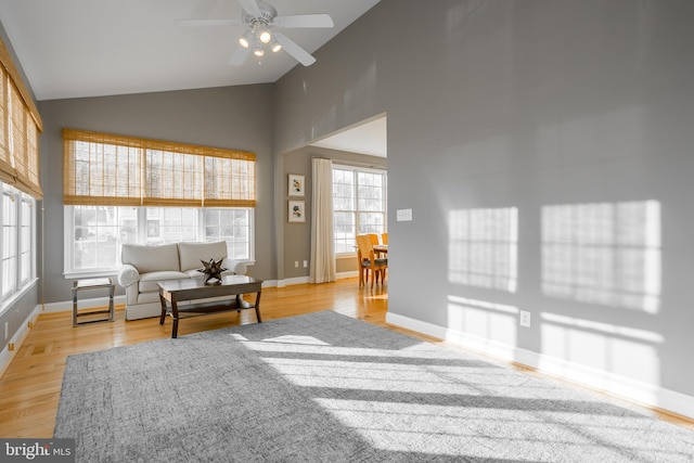 living room with ceiling fan, high vaulted ceiling, and light hardwood / wood-style flooring