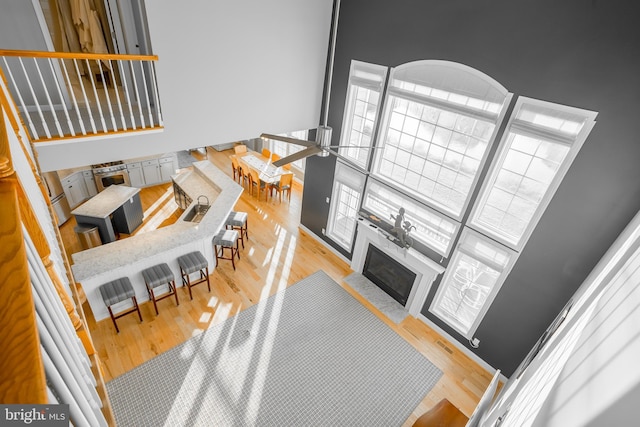 living room featuring ceiling fan, a towering ceiling, sink, and light wood-type flooring