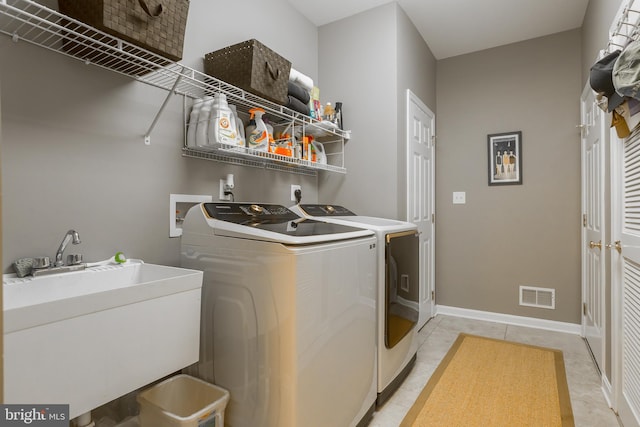 laundry area featuring light tile patterned flooring, sink, and washing machine and dryer