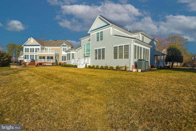 back of house with central AC unit and a yard