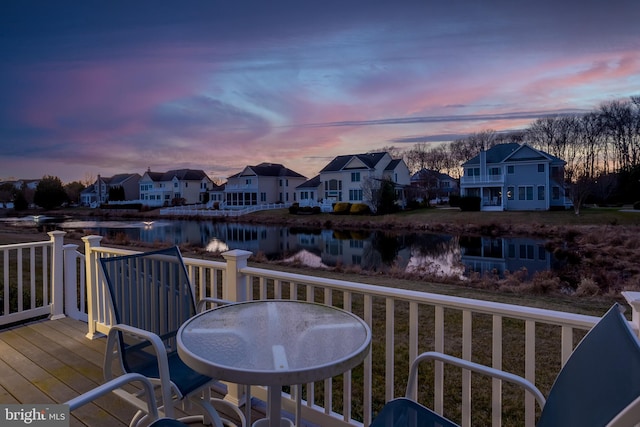 deck at dusk featuring a water view