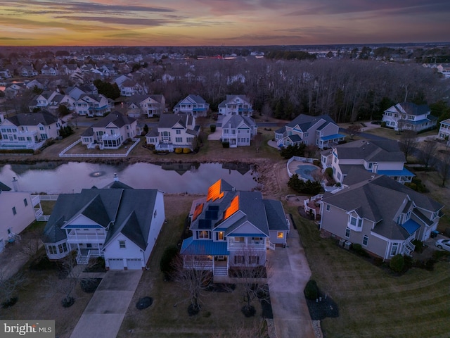 aerial view at dusk featuring a water view