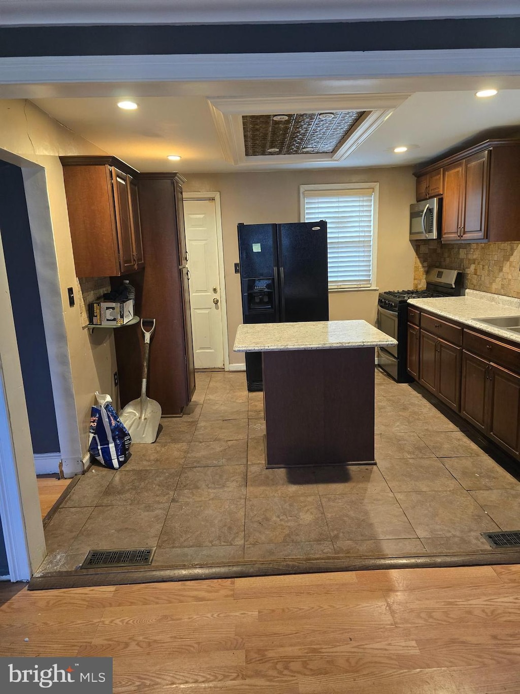 kitchen featuring sink, dark brown cabinets, appliances with stainless steel finishes, a kitchen island, and decorative backsplash