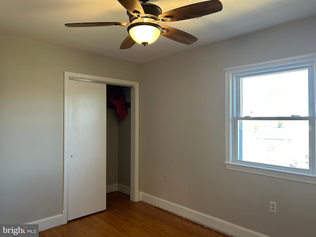 unfurnished bedroom featuring hardwood / wood-style flooring, ceiling fan, and a closet