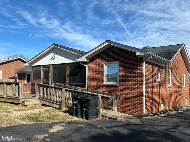 exterior space featuring a wooden deck and a sunroom