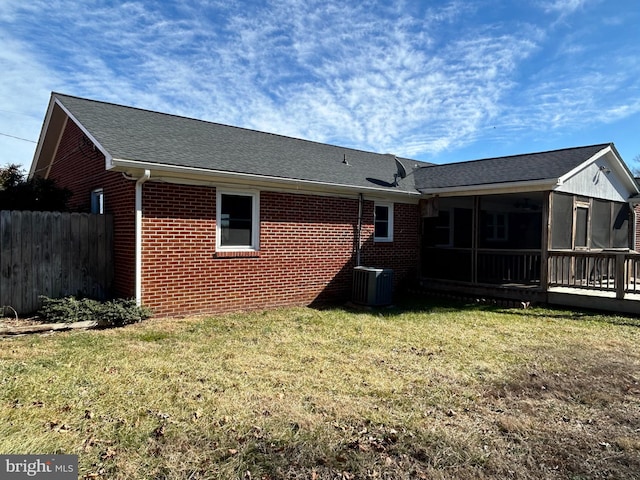 rear view of house featuring cooling unit, a lawn, and a sunroom