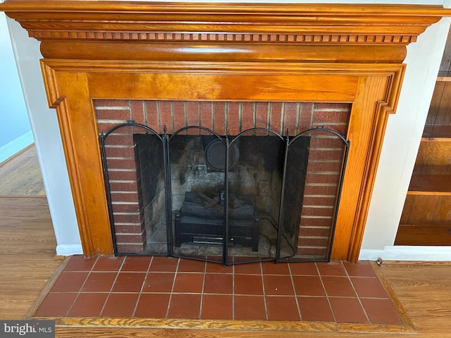 room details featuring a brick fireplace and wood-type flooring