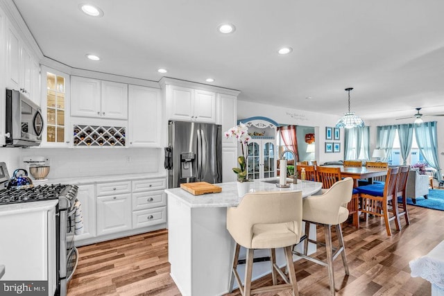 kitchen with pendant lighting, white cabinetry, appliances with stainless steel finishes, and an island with sink