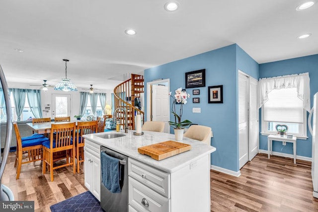 kitchen with sink, a kitchen island with sink, white cabinets, decorative light fixtures, and stainless steel dishwasher