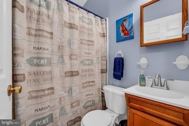 bathroom featuring vanity, walk in shower, and toilet