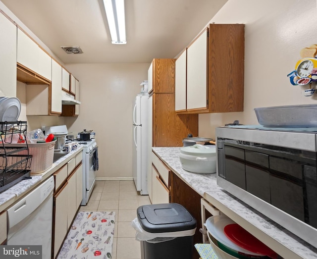 kitchen with white cabinetry, light tile patterned floors, and white appliances