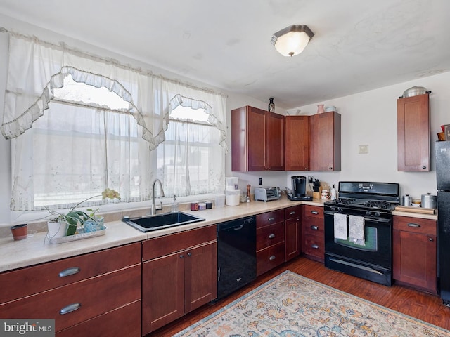 kitchen with reddish brown cabinets, dark wood-style flooring, light countertops, a sink, and black appliances