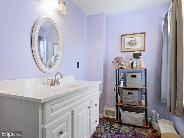 bathroom with visible vents, vanity, baseboards, and wood finished floors