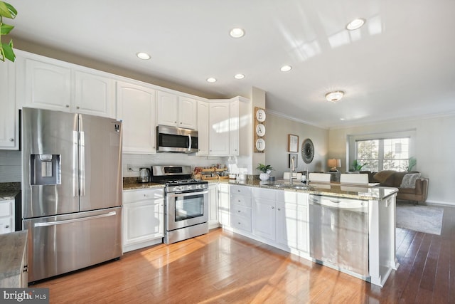 kitchen with light stone counters, white cabinetry, kitchen peninsula, and appliances with stainless steel finishes