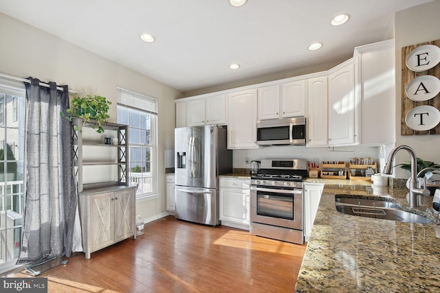 kitchen with white cabinetry, sink, stainless steel appliances, and dark stone counters