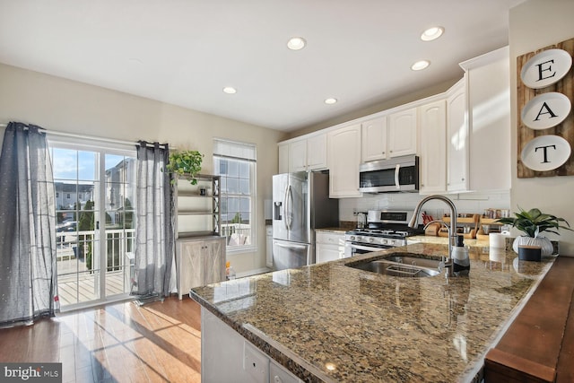 kitchen featuring white cabinetry, sink, dark stone counters, kitchen peninsula, and stainless steel appliances