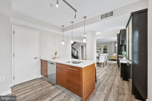 kitchen featuring dishwasher, sink, hanging light fixtures, and light wood-type flooring