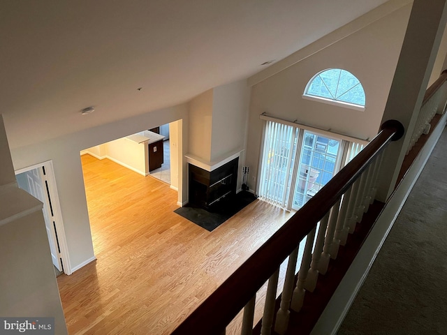 stairway featuring hardwood / wood-style flooring, vaulted ceiling, and a multi sided fireplace