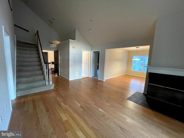 unfurnished living room featuring high vaulted ceiling and light hardwood / wood-style floors