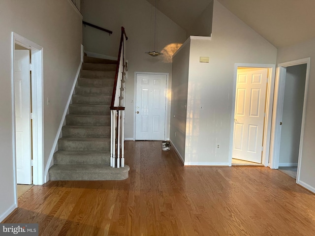 entryway with hardwood / wood-style floors and high vaulted ceiling