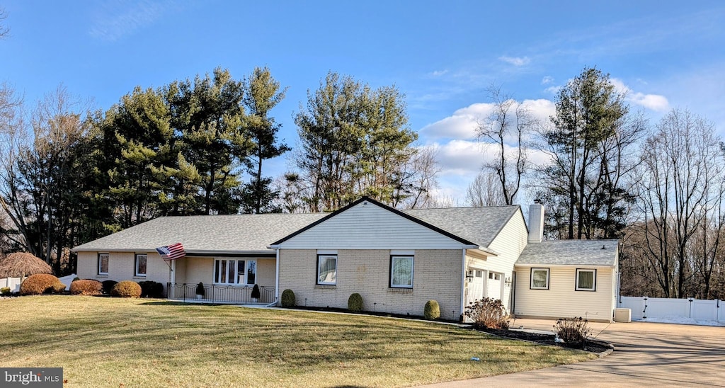 ranch-style house featuring a garage, central AC, and a front yard