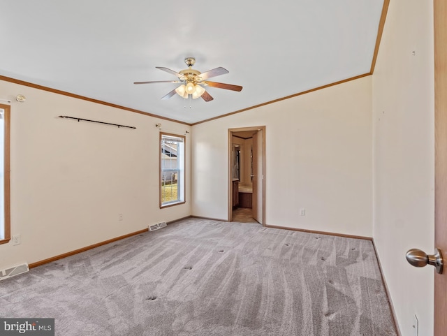 empty room featuring light carpet, ornamental molding, and ceiling fan