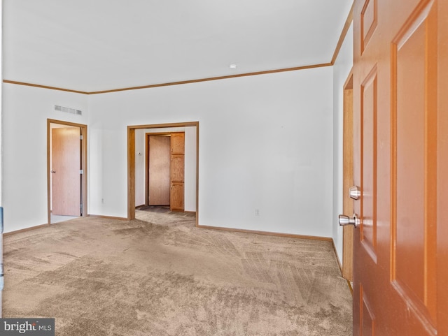 empty room with ornamental molding and carpet