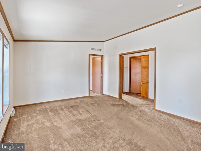 empty room featuring crown molding and light colored carpet