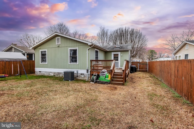 back of house at dusk featuring a deck, crawl space, cooling unit, and a fenced backyard