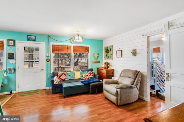 living area featuring a barn door, plenty of natural light, baseboards, and wood finished floors