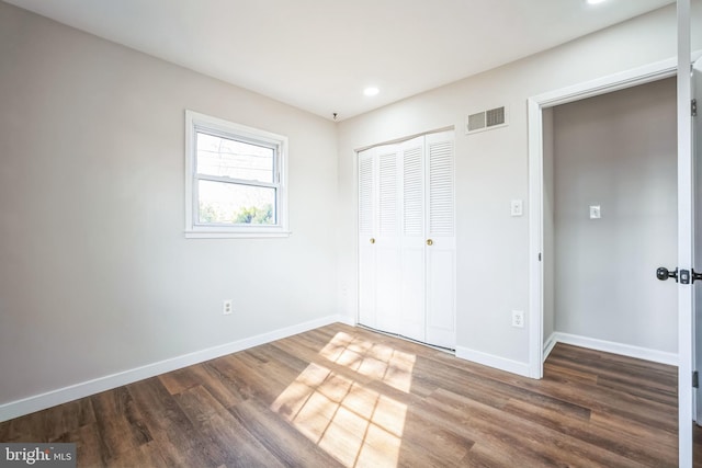 unfurnished bedroom featuring dark hardwood / wood-style flooring and a closet