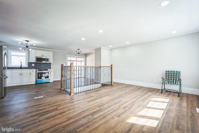 unfurnished living room featuring hardwood / wood-style floors, crown molding, a wealth of natural light, and ceiling fan with notable chandelier