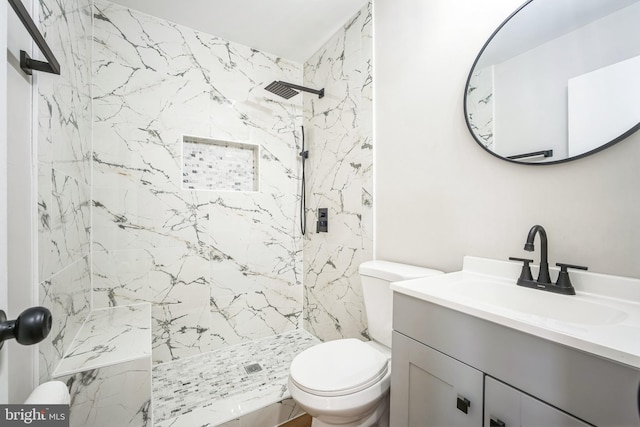 bathroom featuring tiled shower, vanity, and toilet