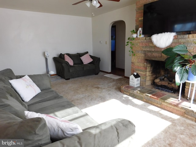 carpeted living room featuring a fireplace and ceiling fan