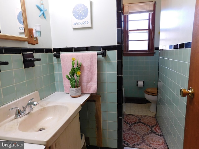 bathroom with tile patterned floors, vanity, toilet, and tile walls