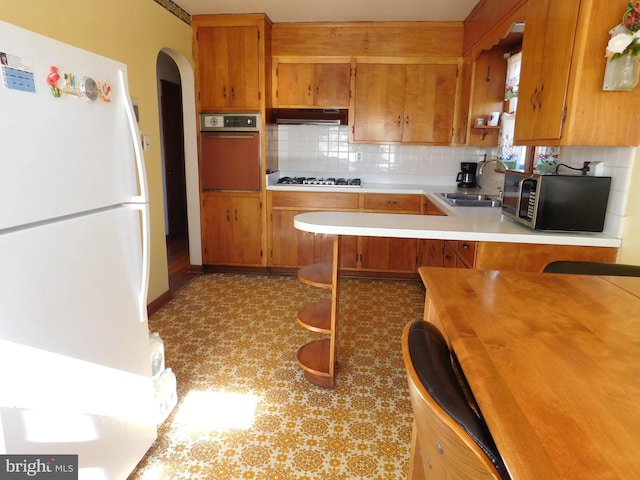 kitchen featuring tasteful backsplash, sink, stainless steel appliances, and kitchen peninsula