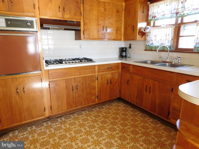 kitchen with sink, backsplash, oven, and stainless steel gas cooktop