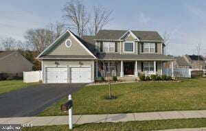 view of front of house featuring a garage, covered porch, and a front lawn