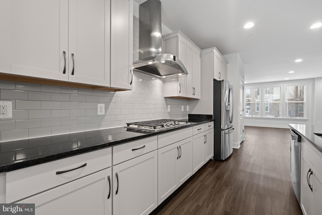 kitchen with appliances with stainless steel finishes, dark hardwood / wood-style floors, tasteful backsplash, white cabinets, and wall chimney exhaust hood