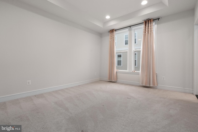 carpeted spare room with a tray ceiling