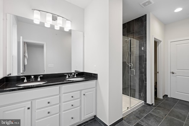 bathroom with a shower with door, vanity, and tile patterned flooring