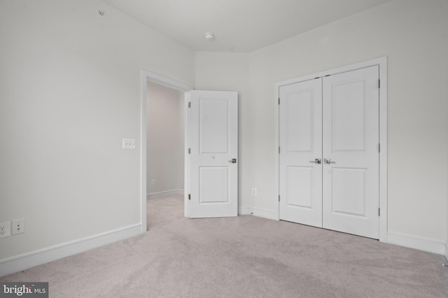 unfurnished bedroom featuring light carpet and a closet