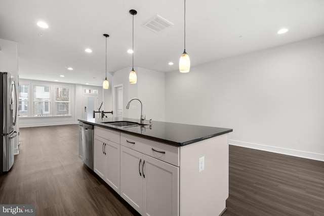 kitchen with stainless steel appliances, a kitchen island with sink, sink, and decorative light fixtures