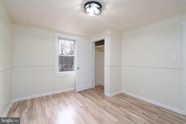 unfurnished bedroom with ornamental molding, light hardwood / wood-style floors, and a closet