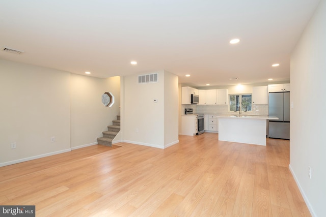 unfurnished living room with sink and light wood-type flooring